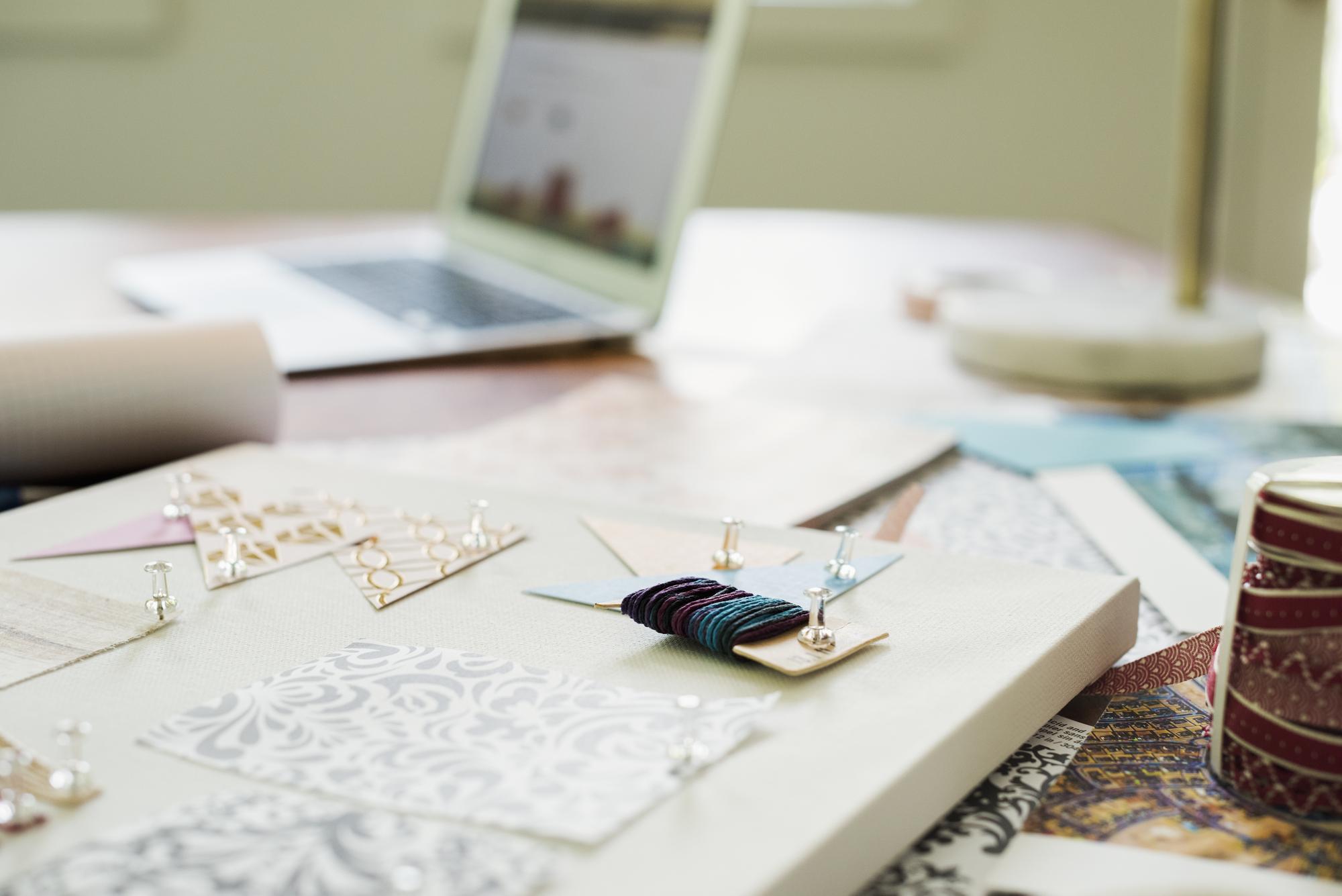 Studio desk with embroidery samples and laptop